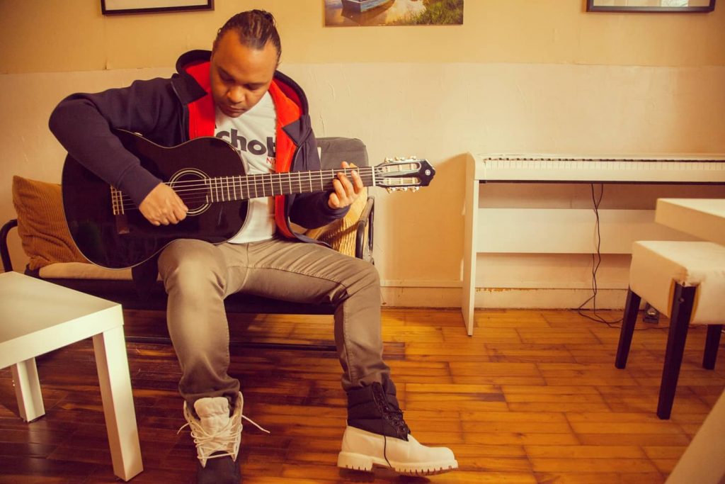 Jonathan HEERAH tenant une guitare près du piano